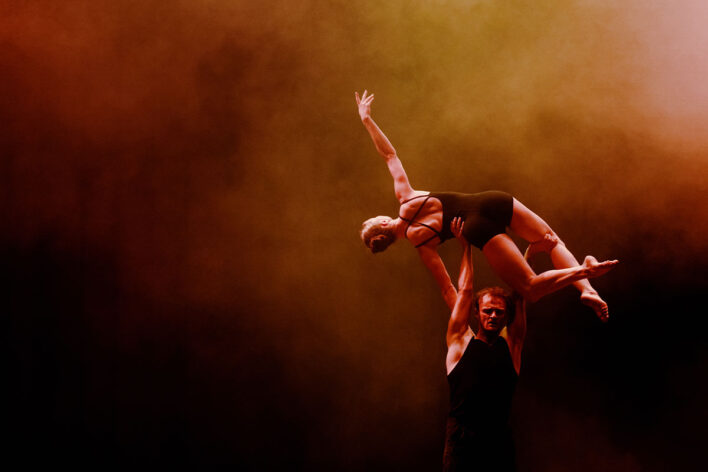 two performers dancing with one above the others head