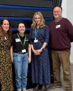 four people standing in front of a wall. emma suckling and emma thorpe from theatre royal on the left hand side and a teacher and councillr Ian Shipp on the right.